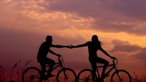 Man and woman couple holding hands and cycling