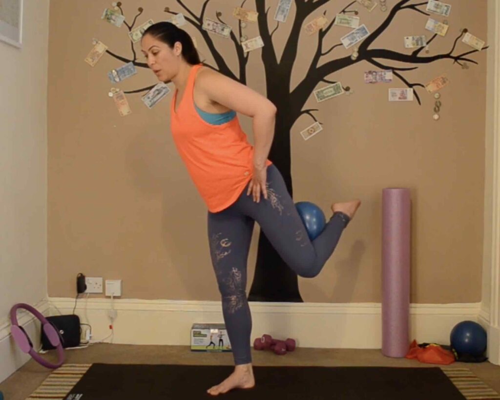 Ceza doing standing Pilates and holding the small ball in the back of the knee.