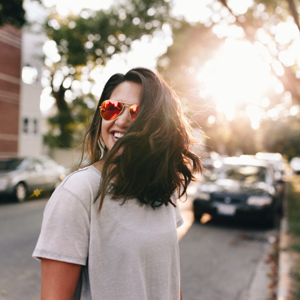 Confident woman with sunglasses on and smiling. 