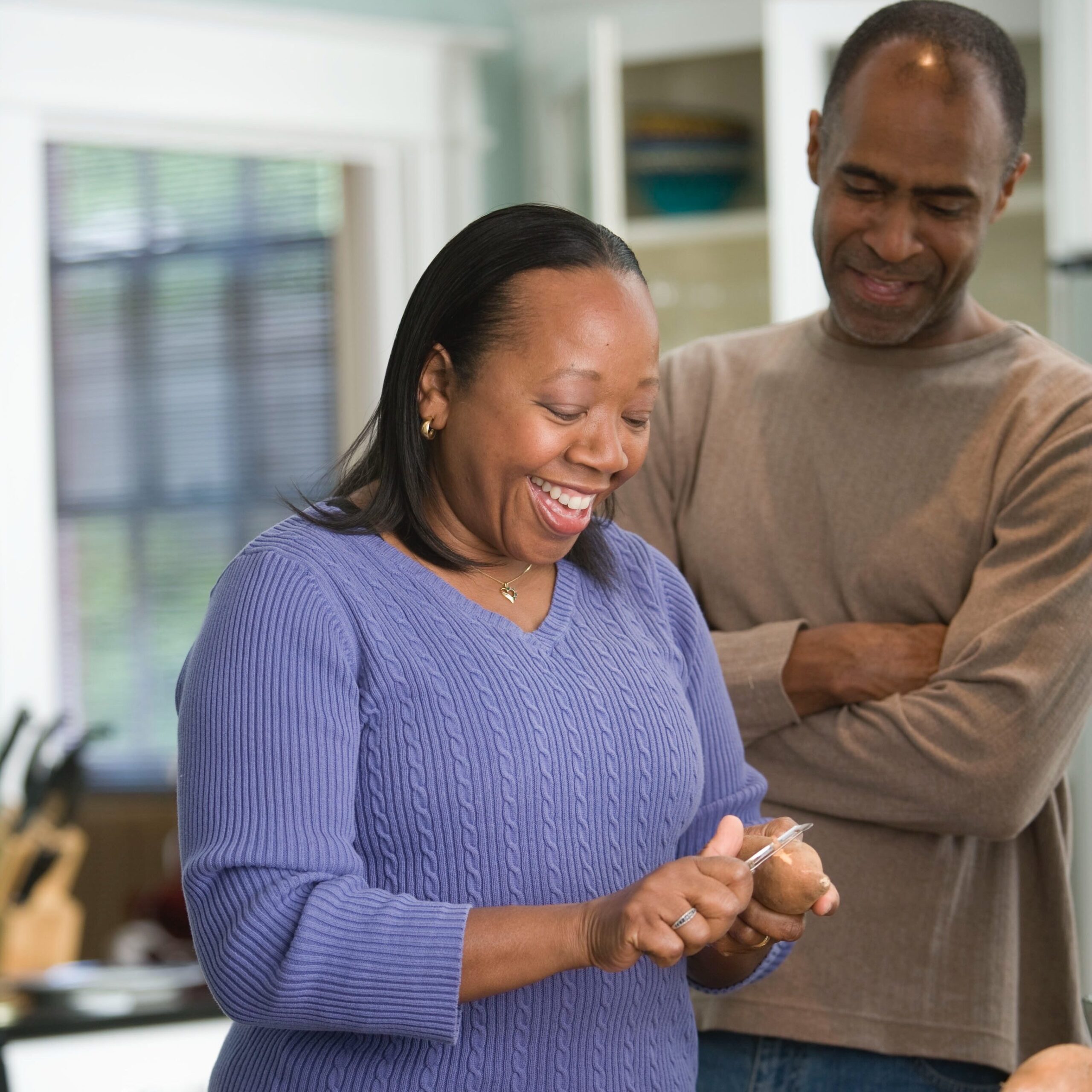 Woman peeling potatoes and laughing and her man standing next to her smiling too. Older couple dating. 
Photo by CDC on Unsplash