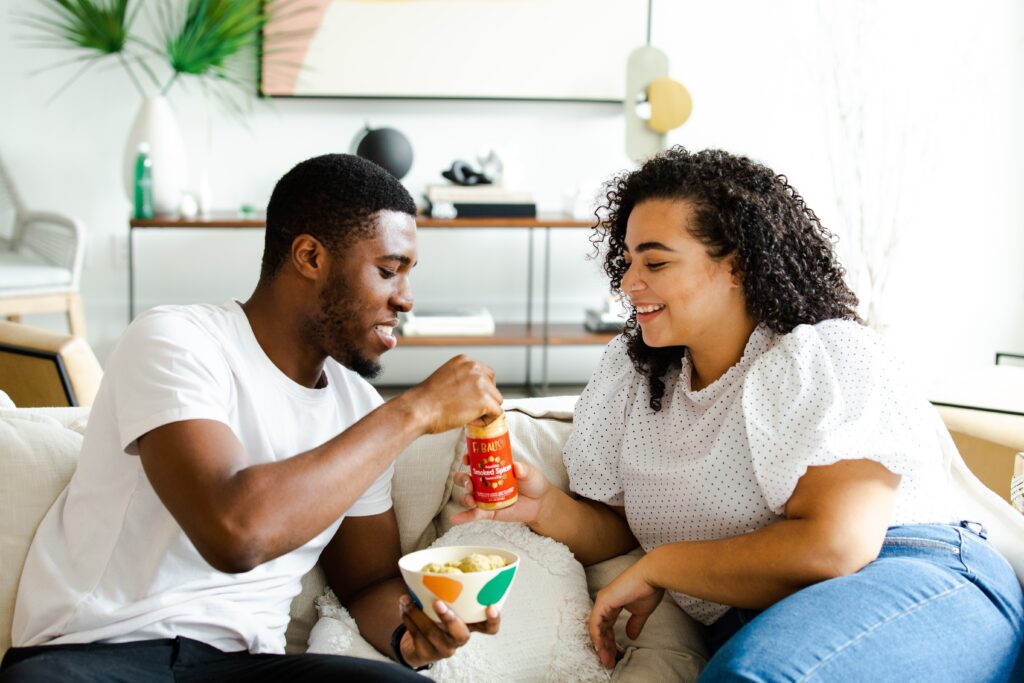 Happy couple eating together on the sofa. Photo by No Revisions on Unsplash