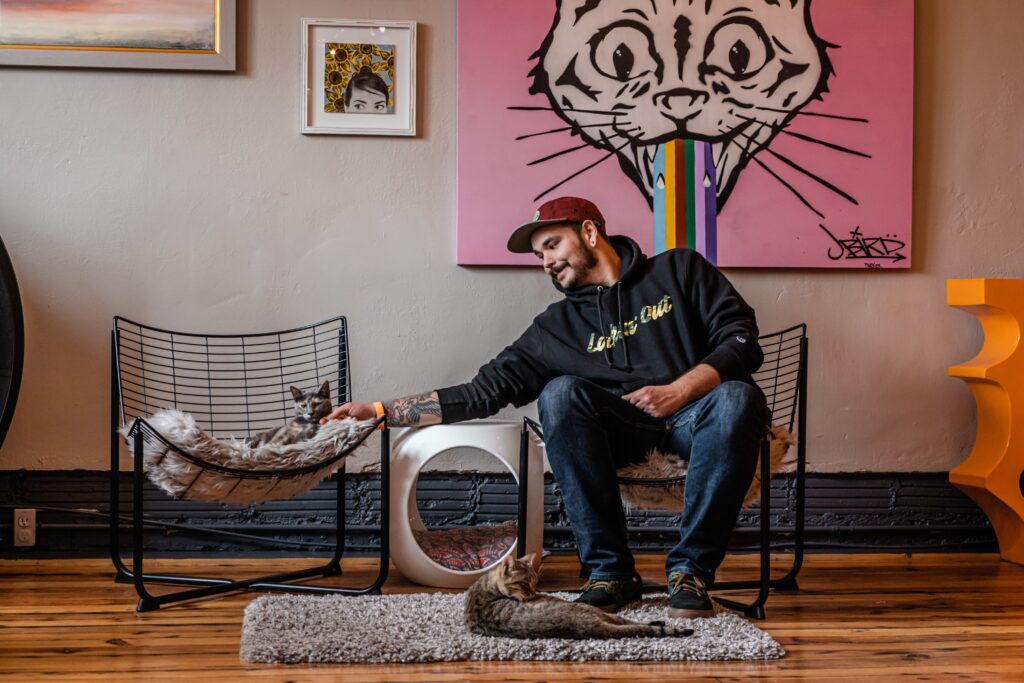 Man in a cat café with 2 cats. Photo by Camden & Hailey George on Unsplash. 