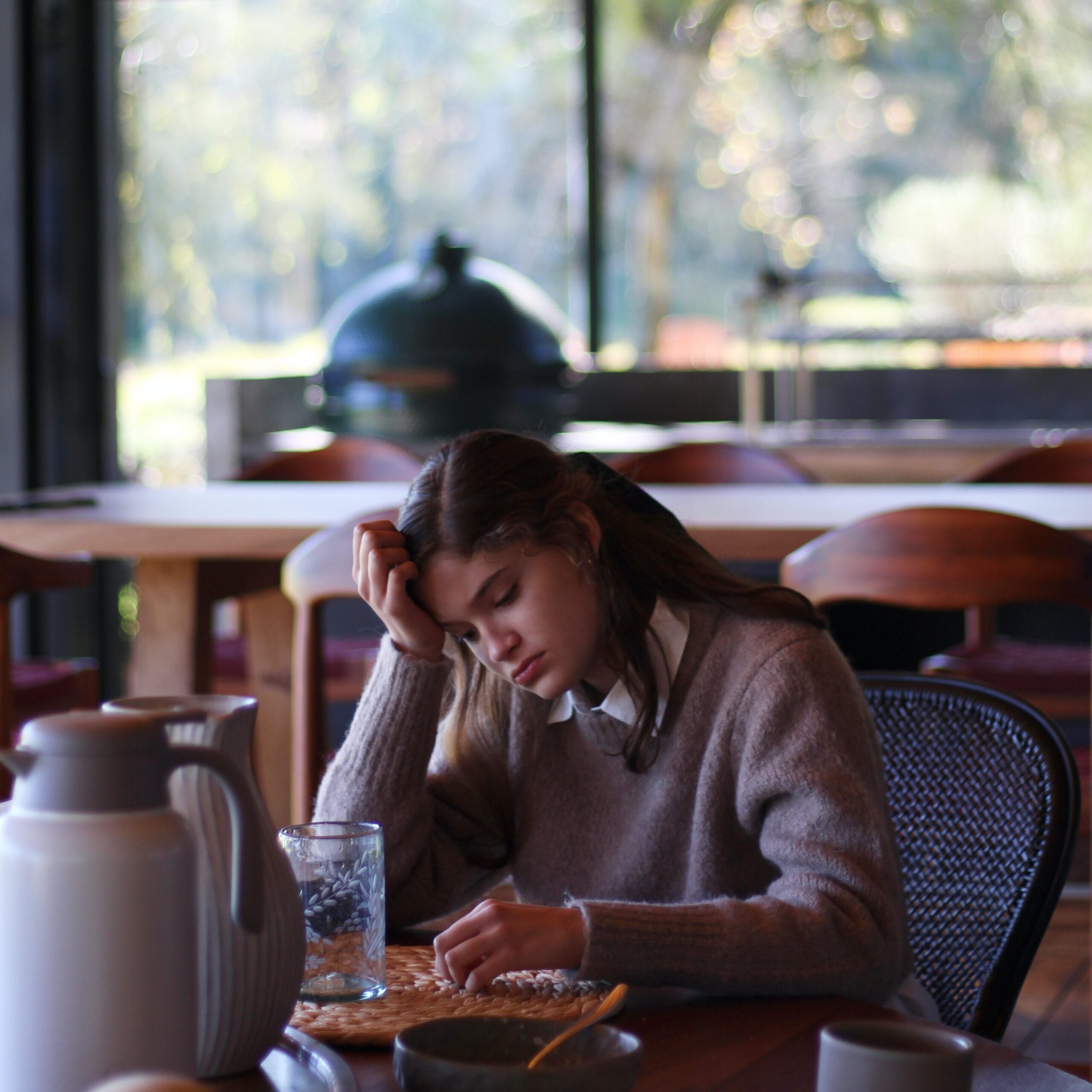 Woman pondering while sitting at a table in a cafe. Photo by Lucia Macedo on Unsplash