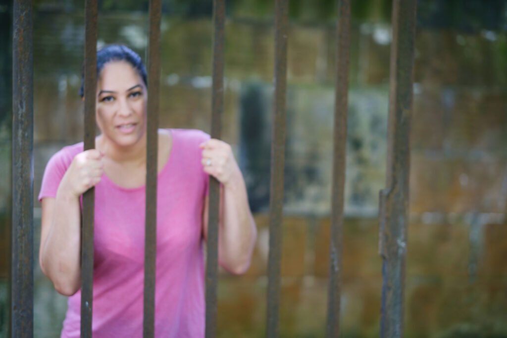 Woman trapped behind bars, which represent how she feels trapped in her relationship with red flags. 