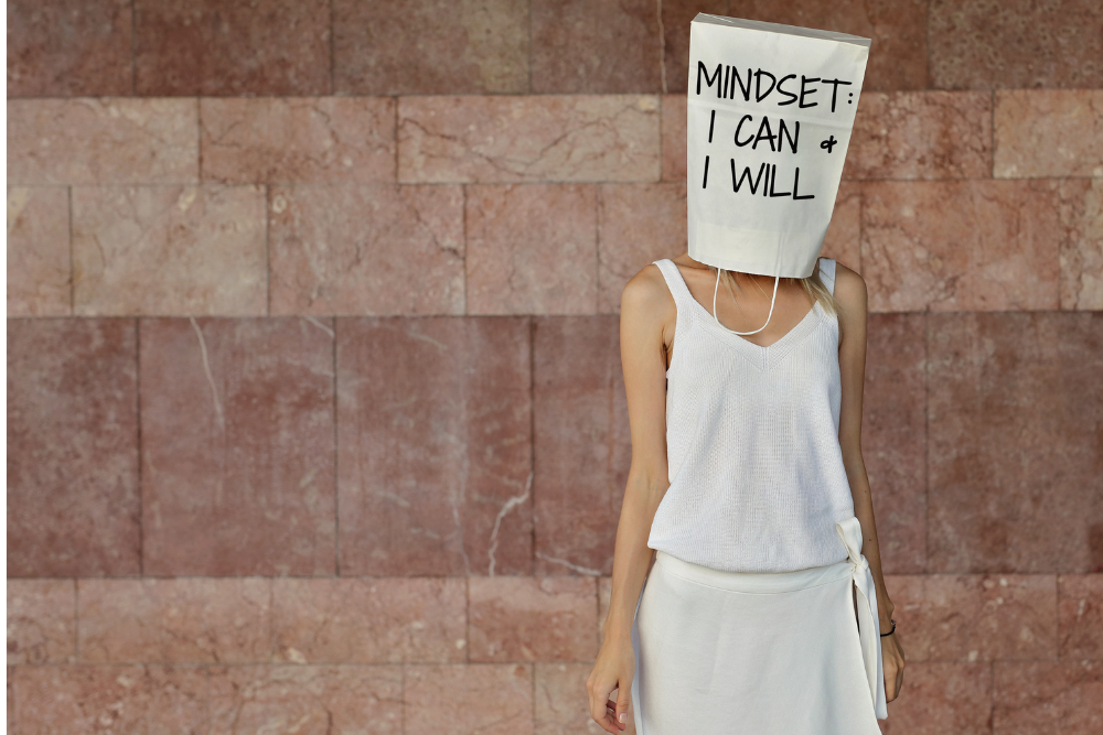 A woman with a bag over her head that says "Mindset: I can & I will". 
