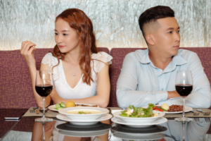 Man and woman sitting at the table on a date. Both looking in opposite directions, clearly bored.