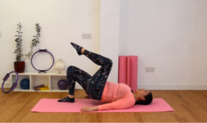 Free Pilates workout, instructor doing a leg lift in shoulder bridge.