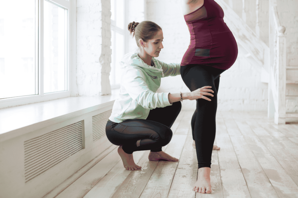 Instructor helping pregnant client get into the correct Pilates position. 