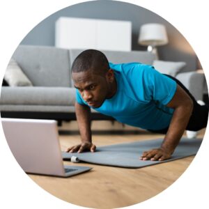 Man doing Pilates push up while following instructor online.