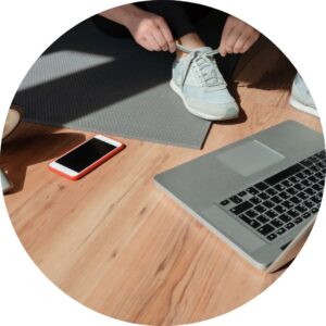 Image of a laptop, phone and a woman putting on trainers.