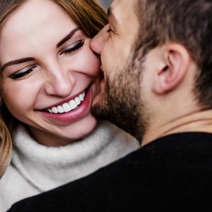 Man and woman smiling and kissing.